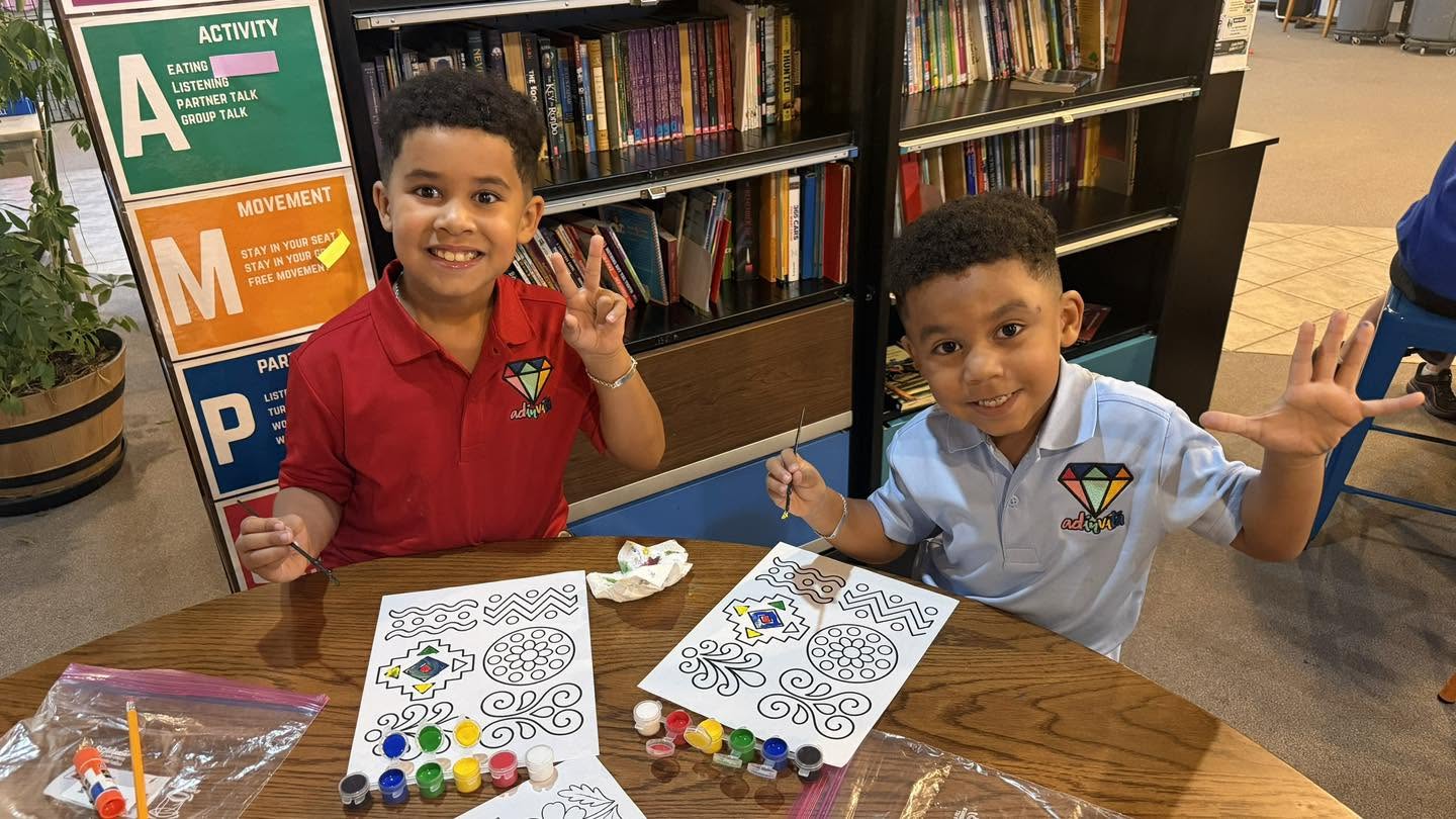 Two smiling Adinvita students painting colorful designs in the classroom