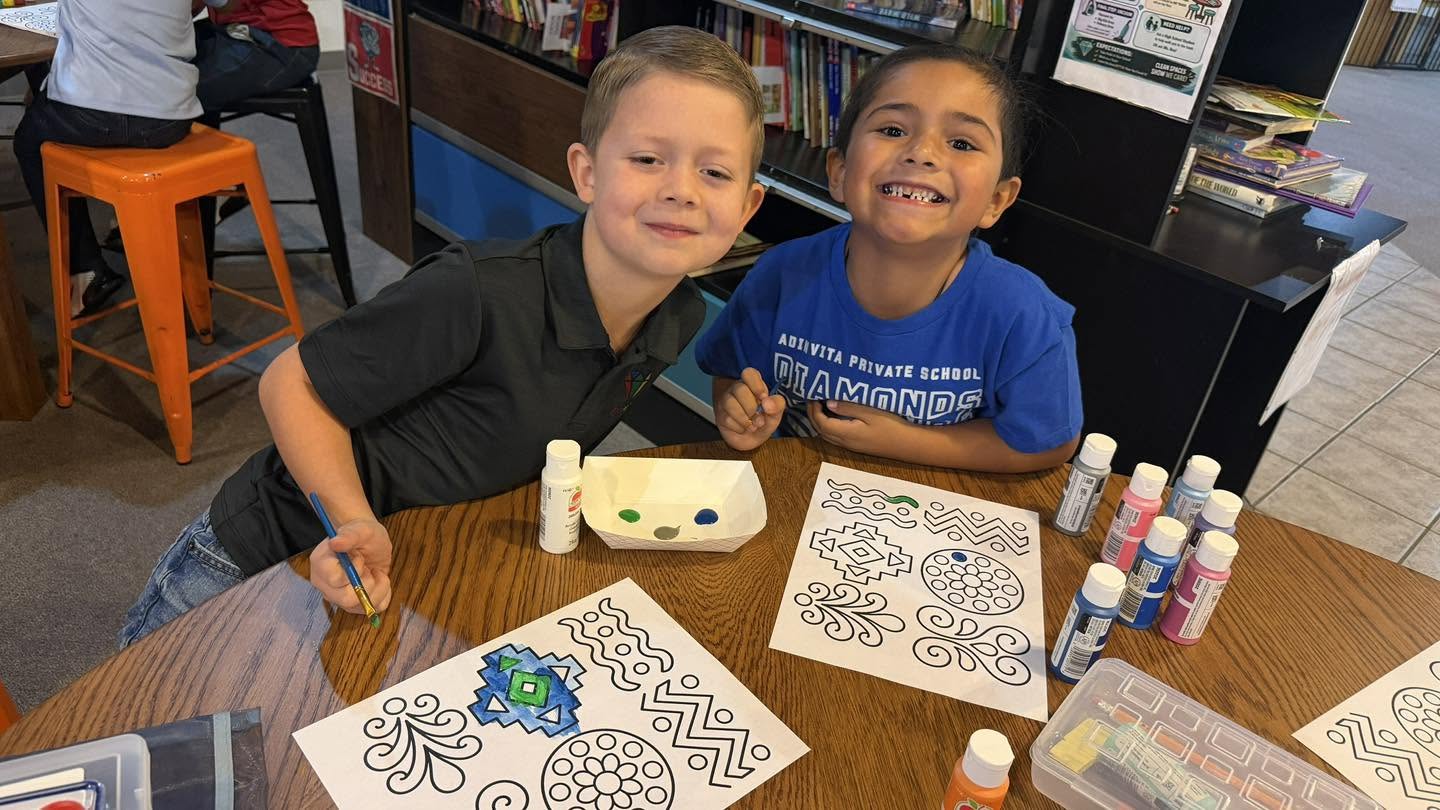 Two Adinvita students smiling while painting colorful designs together